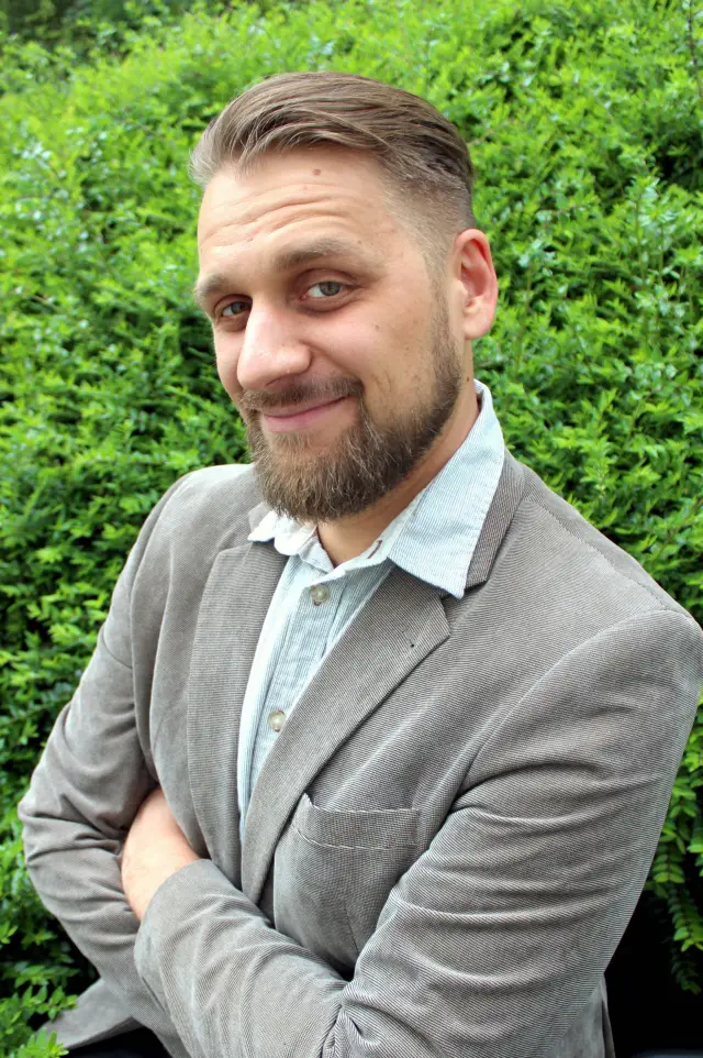 Sebastian Ohlerth, Psychologischer Psychotherapeut, vor einer Hecke